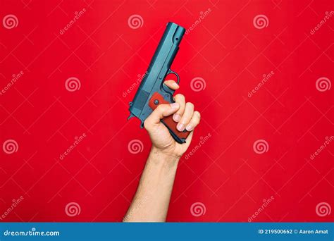 Beautiful Hand Of Man Holding Gun Over Isolated Red Background Stock