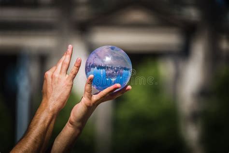 Person Holding Up A Crystal Ball With A Reflection Of A Building Stock