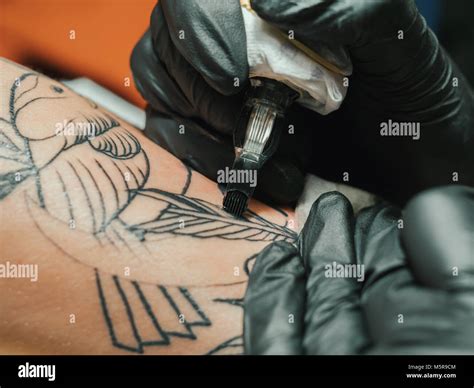 Tattoo Artist At Work Woman In Black Latex Glove Tattooing A Young Man
