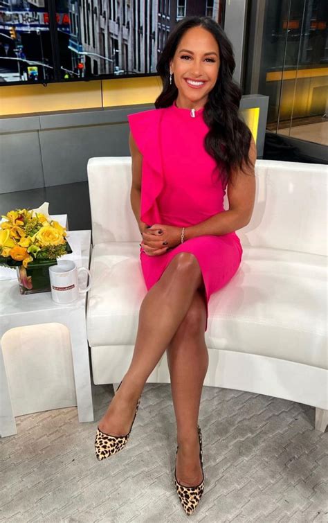 A Woman In A Pink Dress Is Sitting On A White Couch And Smiling At The Camera