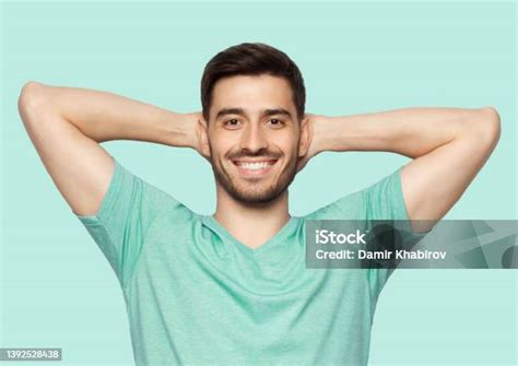 Young Man Standing With Arms Behind Head Relaxing Peacefully In Free