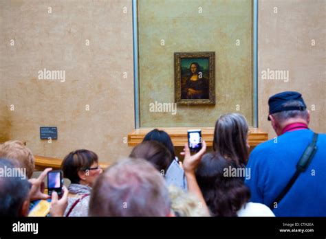 Visitors Viewing The Mona Lisa Painting In The Louvre Museum In Paris