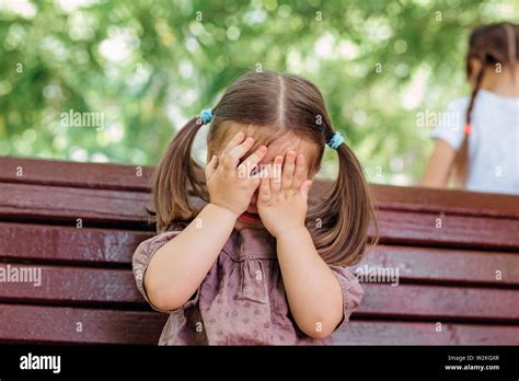 Little Girl Is Playing Hide And Seek Hiding Face In Park Stock Photo