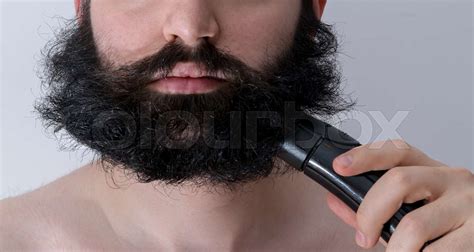 A Man Trimming His Ungroomed Beard With Long Messy And Untrimmed Hair
