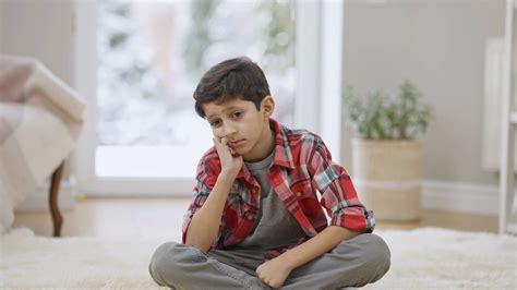 Sad Frustrated Middle Eastern Boy Sitting On Carpet At Home Thinking