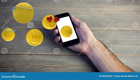 Digital Composite Image Of Hand Holding Smart Phone While Emojis Coming