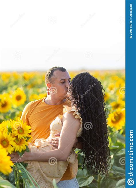 A Beautiful Young Couple A Man And A Woman Kissing In A Field Of Sunflowers At Sunset Stock