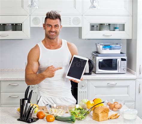 hombre hermoso feliz que cocina en cocina en casa imagen de archivo imagen de alegre cocinero