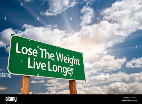 Lose The Weight Live Longer Green Road Sign With Dramatic Clouds Sun