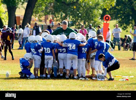 Young Football Players Age 10 Huddling Around Coach Listening To His
