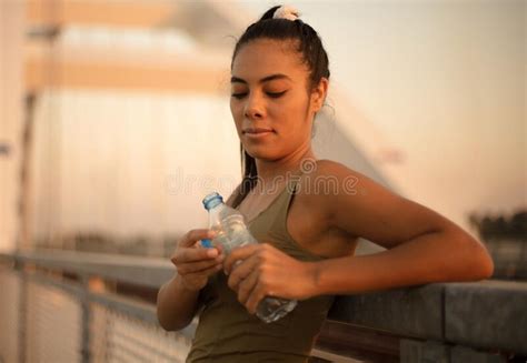 Sports Young Woman Standing On The Bridge And Drinking Water After