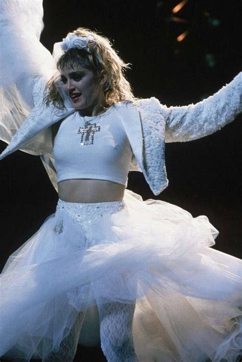 a woman in a white outfit with wings on her head and arms outstretched dancing