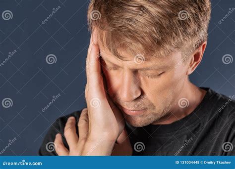 A Man Holds His Hands On His Head On Blue Background Headache Or