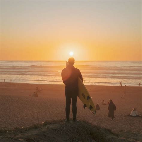 Silueta Del Hombre Que Sostiene La Tabla De Surf Caminando En La Playa