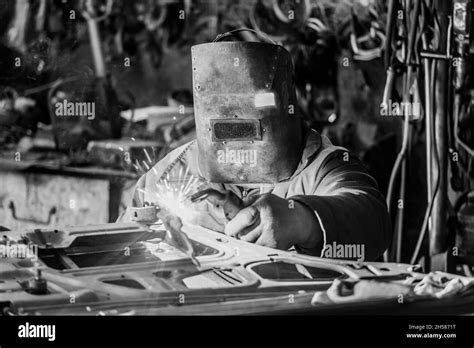 The welder in the protective shield is engaged in welding work on iron