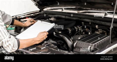Automobile Mechanic Repairman Checking A Car Engine With Inspecting