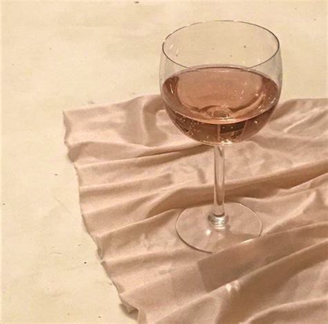 A Glass Of Wine Sitting On Top Of A White Table Cloth Next To A Bottle