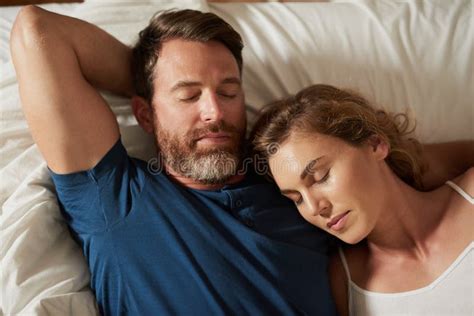 in love the only way to sleep a happy middle aged couple relaxing in bed together stock image