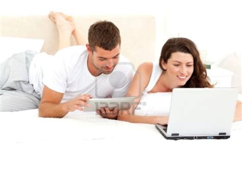 Cute Couple Working Together On Their Laptop Lying On Their Bed Royalty