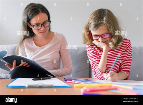 Young Woman Teacher Teaches Primary School Girl Individual Private Education Lessons At Home