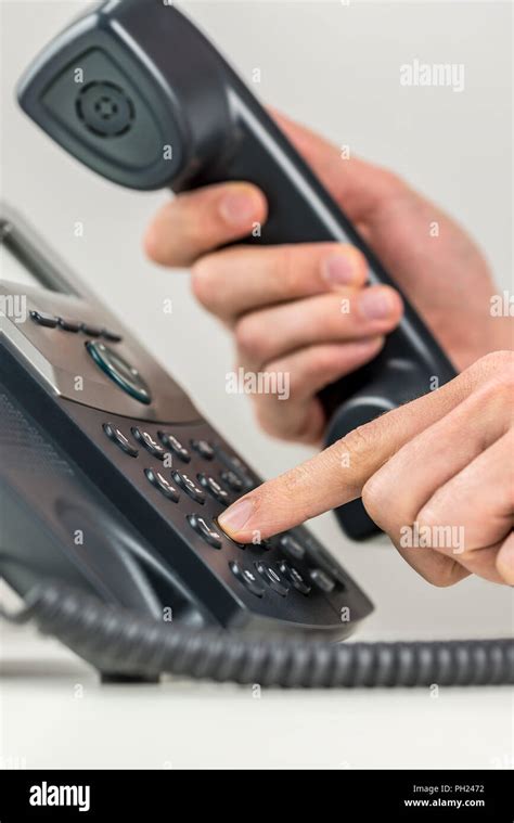 Close Up View Of The Hands Of A Man Dialing Out On A Landline Telephone