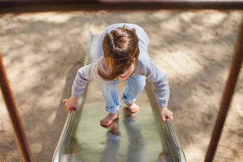 Girl Climbing Up Metal Slide At Playground Windblown Hair By Amanda