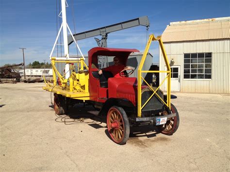 An Old Red And Yellow Truck Parked In Front Of A Building With A Crane