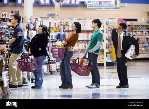 People Waiting In Line With Shopping Baskets At Grocery Store Stock