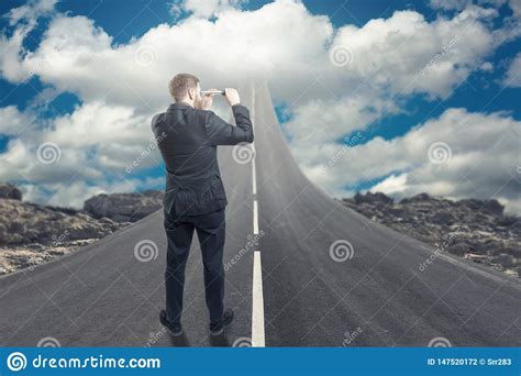 Businessman Standing On Road That Goes Up To The Sky Stock Photo