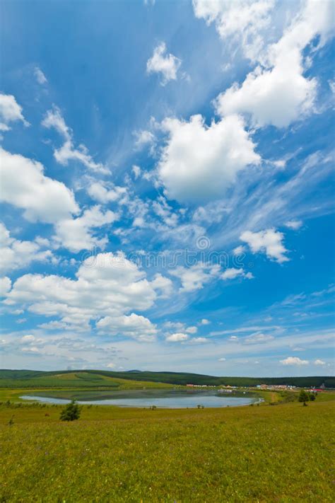 Lake And Green Grass Under The Blue Sky And White Clouds Stock Photo