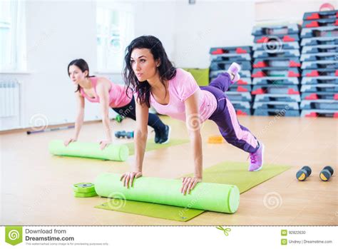 Fit Woman Stretching On Floor Using Foam Roller Doing Plank Exercise
