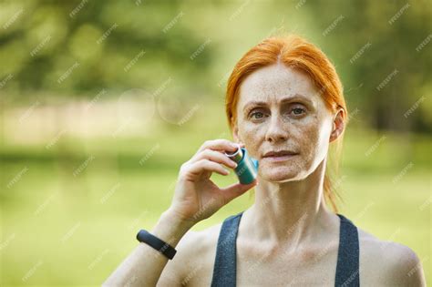 premium photo portrait of serious freckled mature woman using inhaler to prevent asthma attack
