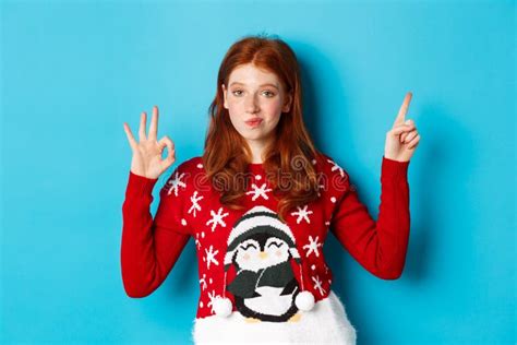 Merry Christmas Cheerful Redhead Girl In Xmas Sweater Pointing Finger At Upper Right Corner