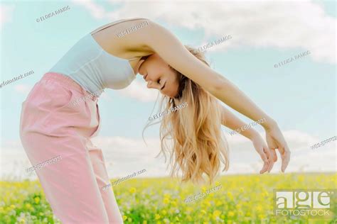 Young Woman Bending Over In A Flower Meadow In Spring Stock Photo