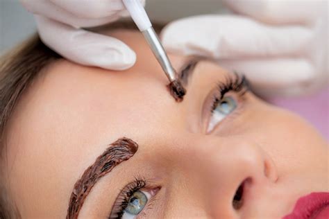 Close Up Photo Of Beautician Applying Dye On Womans Eyebrows Stock