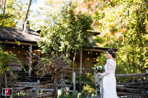 Portrait Of Bride Outside With Bouquet And Farm House At Farm Wedding
