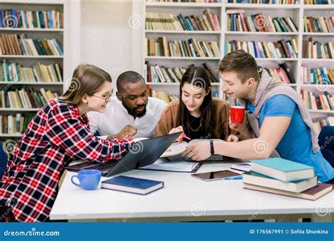 Young Multiethnical College Students At The Library Studying Together