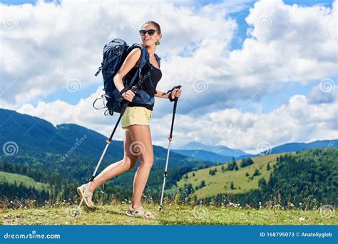 Woman Hiker Hiking On Grassy Hill Wearing Backpack Using Trekking