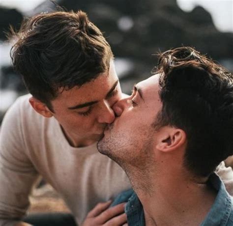 Two Men Are Kissing Each Other On The Beach