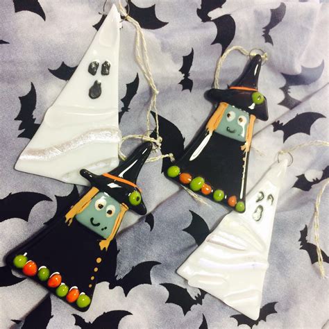 Three Halloween Decorations Are Hanging On A Sheet With Bats And Pumpkins In The Background