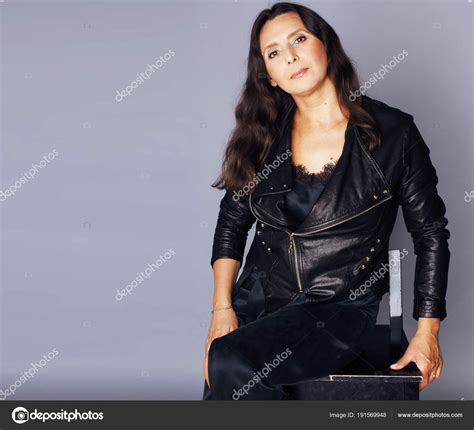 Pretty Brunette Confident Mature Woman Sitting On Chair In Studi Stock