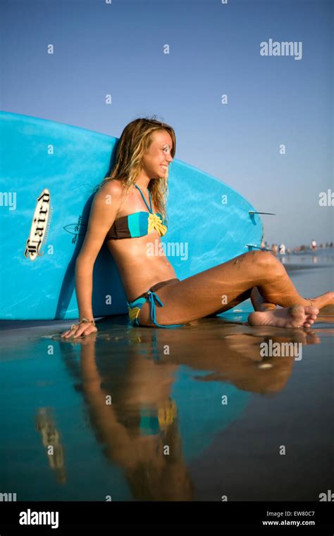 Süße Teenager Blondine genießt den Tag am Strand mit Surfbrett