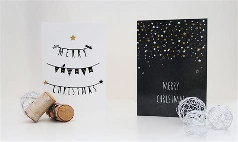 two christmas cards and a wine cork on a white table with black paper one has a merry christmas