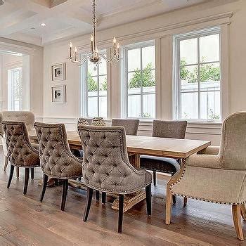 Stunning monochromatic dining room boasts exposed brick walls painted white lined with an l shaped light gray upholstered dining banquette facing a round marble top dining table and light grey french x back chairs illuminated by a brass and glass lantern. Espresso Wood Dining Table with Tolix Chairs - Cottage - Dining Room