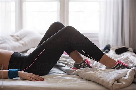 Woman In Sports Leggings And Sneakers Lying On The Bed By Lumina