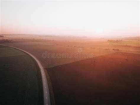 Foggy Sunrise Over Road Surrounded By Agriculture Fields Early Autumn