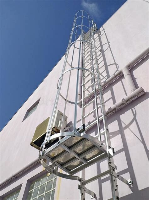 Low Angle View Of An Exterior Vertical Fixed Ladder With Safety Cage In