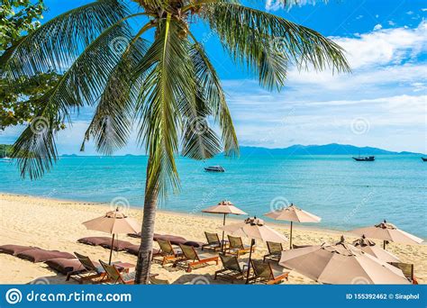 Beautiful Tropical Beach Sea And Ocean With Coconut Palm Tree And Umbrella And Chair On Blue Sky