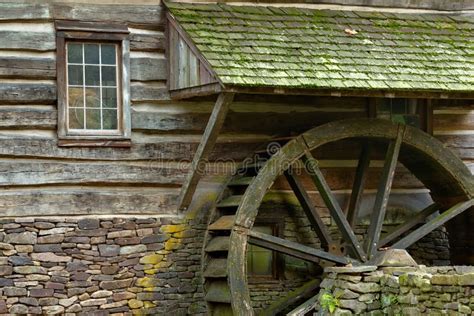Wooden Water Paddle Wheel And Mossy Stones On The Side Of A Old Stock
