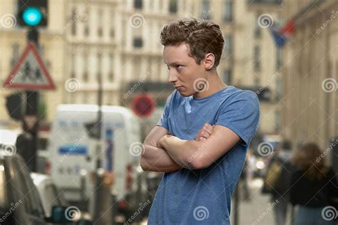 Upset Teen Boy Standing Alone On Blurred City Street Stock Photo
